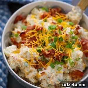 loaded baked potato salad in a bowl with a wooden spoon.