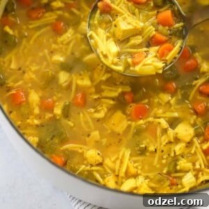 A bowl of easy chicken noodle soup with a spoon, garnished with fresh herbs.