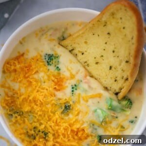 Creamy Broccoli & Cheddar Perfection 2 broccoli cheese soup in a white bowl with a piece of bread on the side.