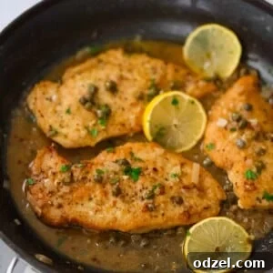 Three chicken breasts piccata in a skillet with sauce and lemon slices.