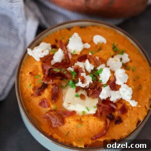 Mashed sweet potatoes with goat cheese and bacon on top, garnished with chives.