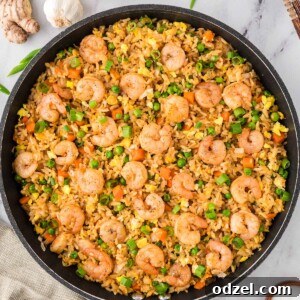 Shrimp fried rice in a large skillet with onions and ginger on the side.