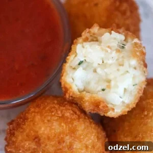 Three cheese arancini with marinara sauce on the side.