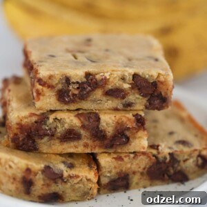 Chocolate banana bars on a plate with ripe bananas in the background, a delicious and easy treat.