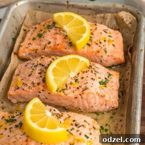 three salmon fillets with lemon wedges on top.