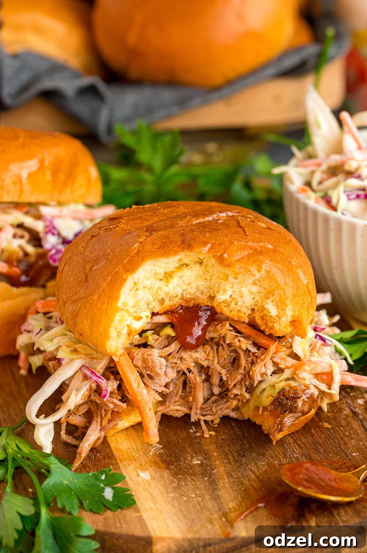 Four delicious pulled pork sandwiches garnished with fresh coleslaw and served on a rustic wooden board.