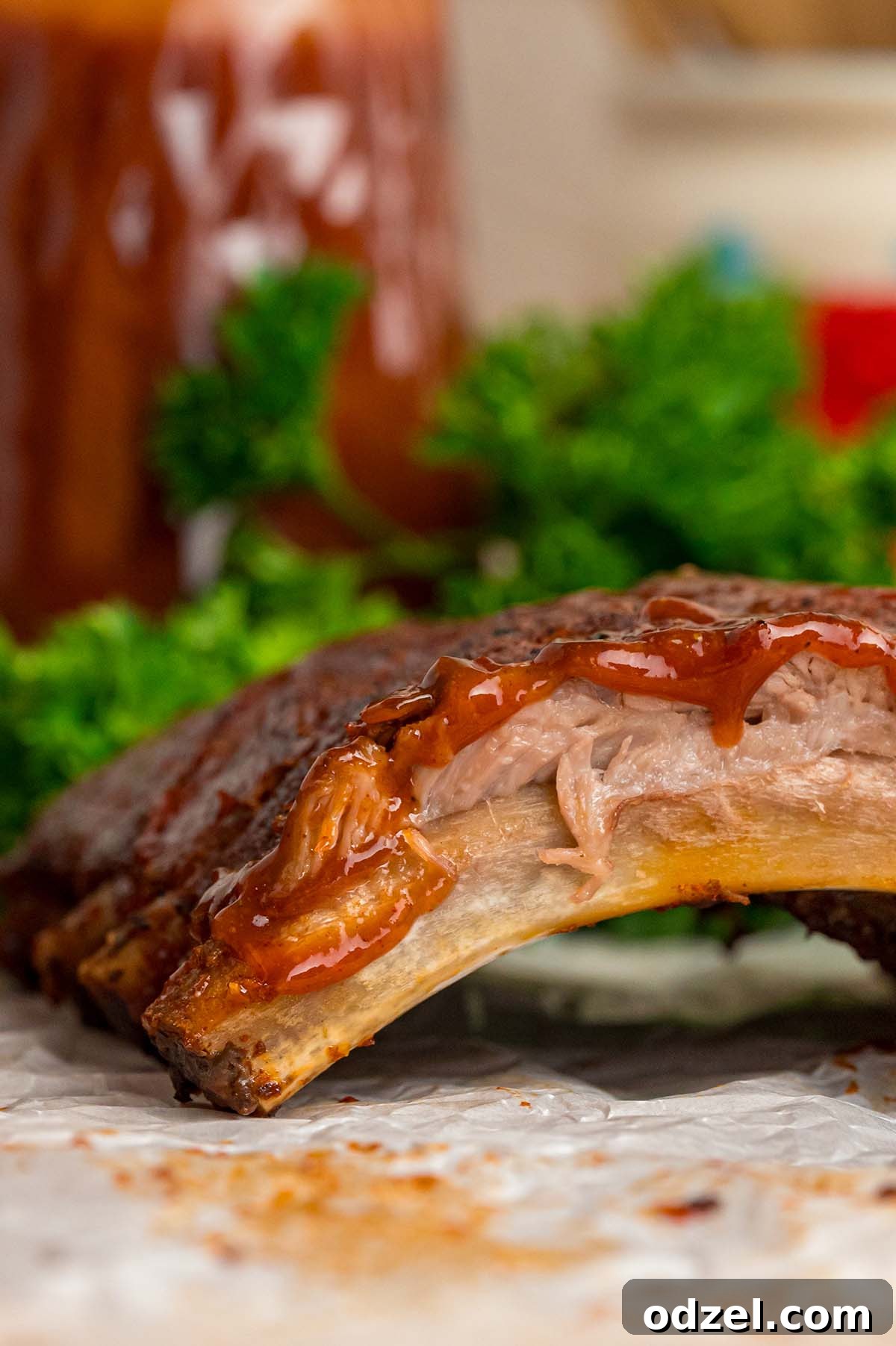 A close-up shot of individual BBQ ribs, glistening with sauce and perfectly cooked, showing their tender texture.