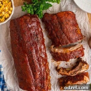 Two slabs of perfectly cooked, glossy oven baked BBQ ribs, slathered in delicious barbecue sauce, ready to be served.