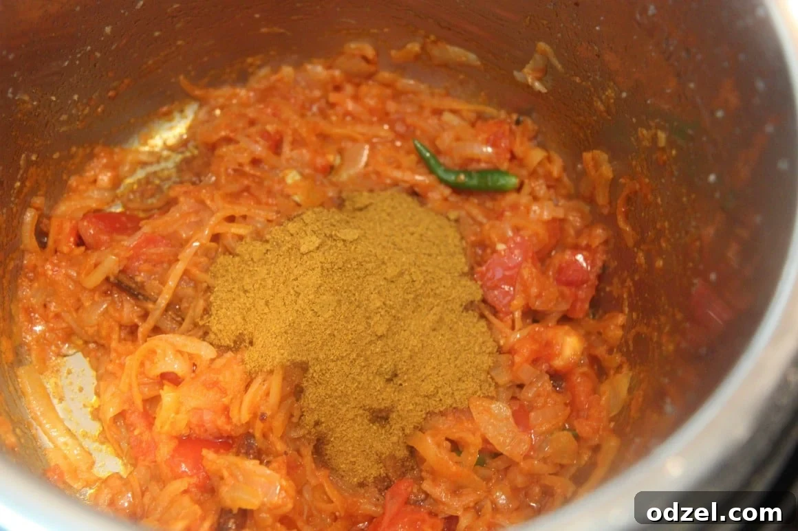 A colorful mixture of finely chopped vegetables and whole spices, including green chilies, ginger, garlic, cinnamon stick, cloves, and cardamoms.