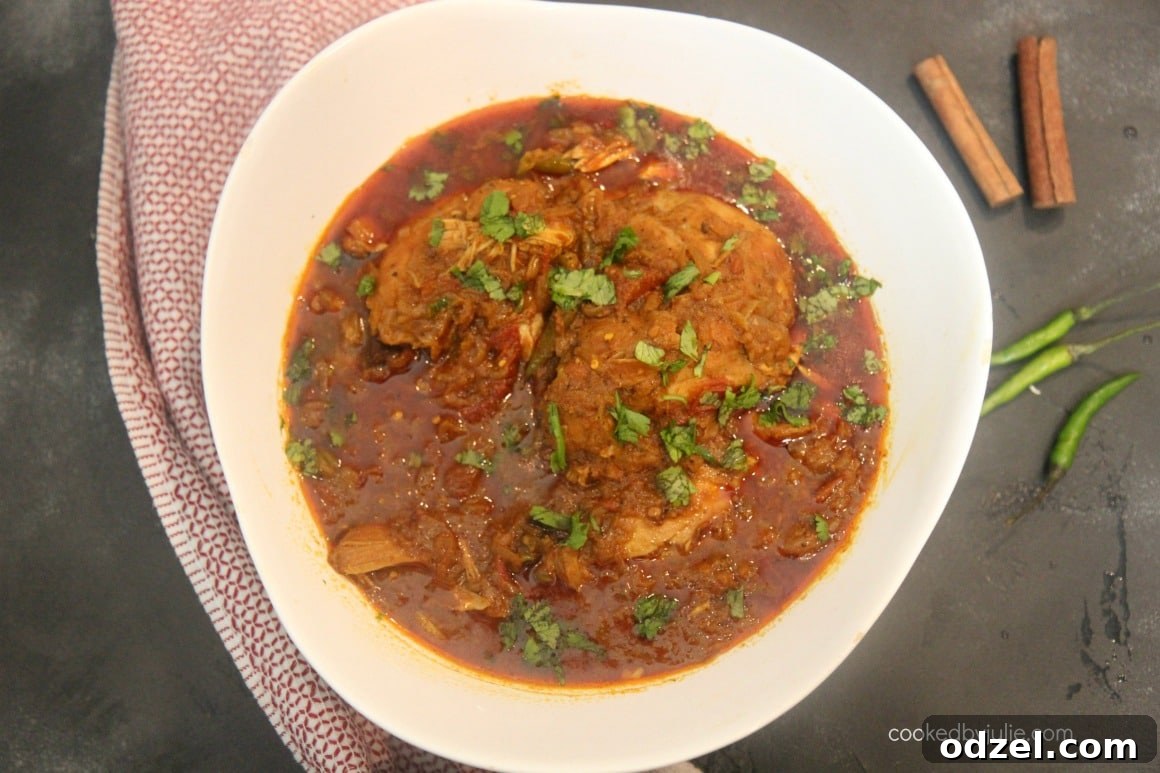Cooked pressure cooker chicken curry, steaming hot and ready to be served from the Instant Pot. The chicken is tender, and the sauce is rich and vibrant.