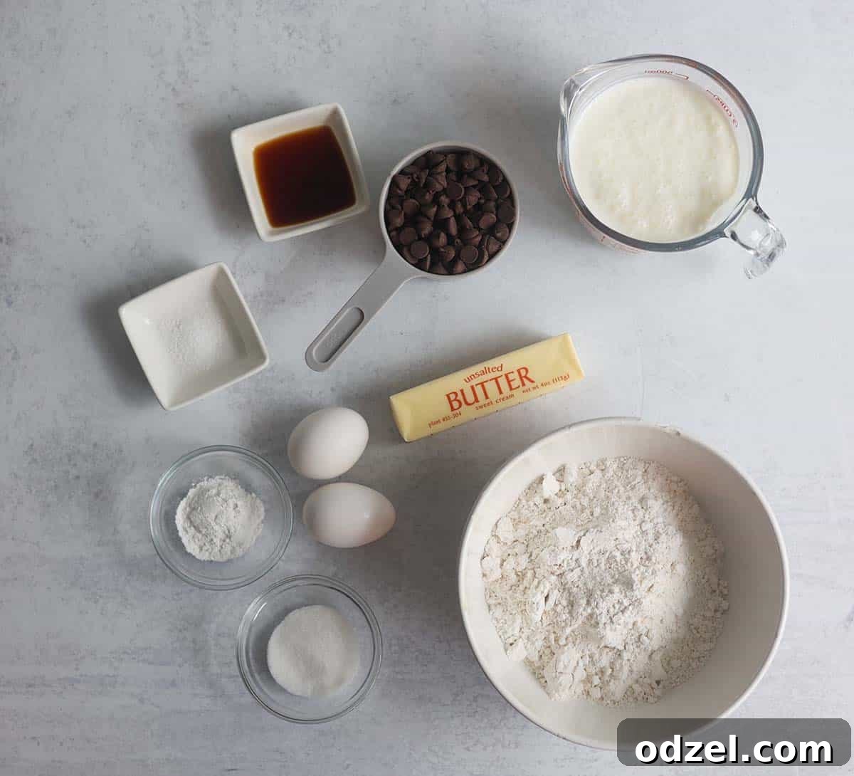 Neatly arranged waffle ingredients: buttermilk, flour, eggs, butter, and chocolate chips, ready for preparation.