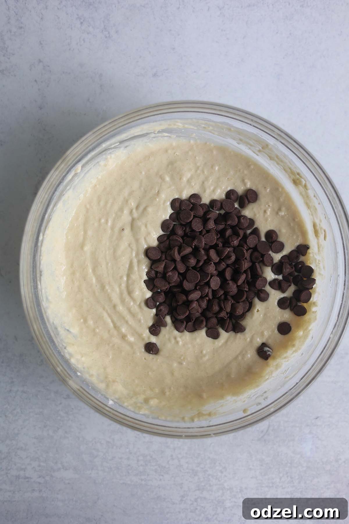A glass bowl filled with thick, lumpy buttermilk chocolate chip waffle batter, glistening and ready for the waffle iron.