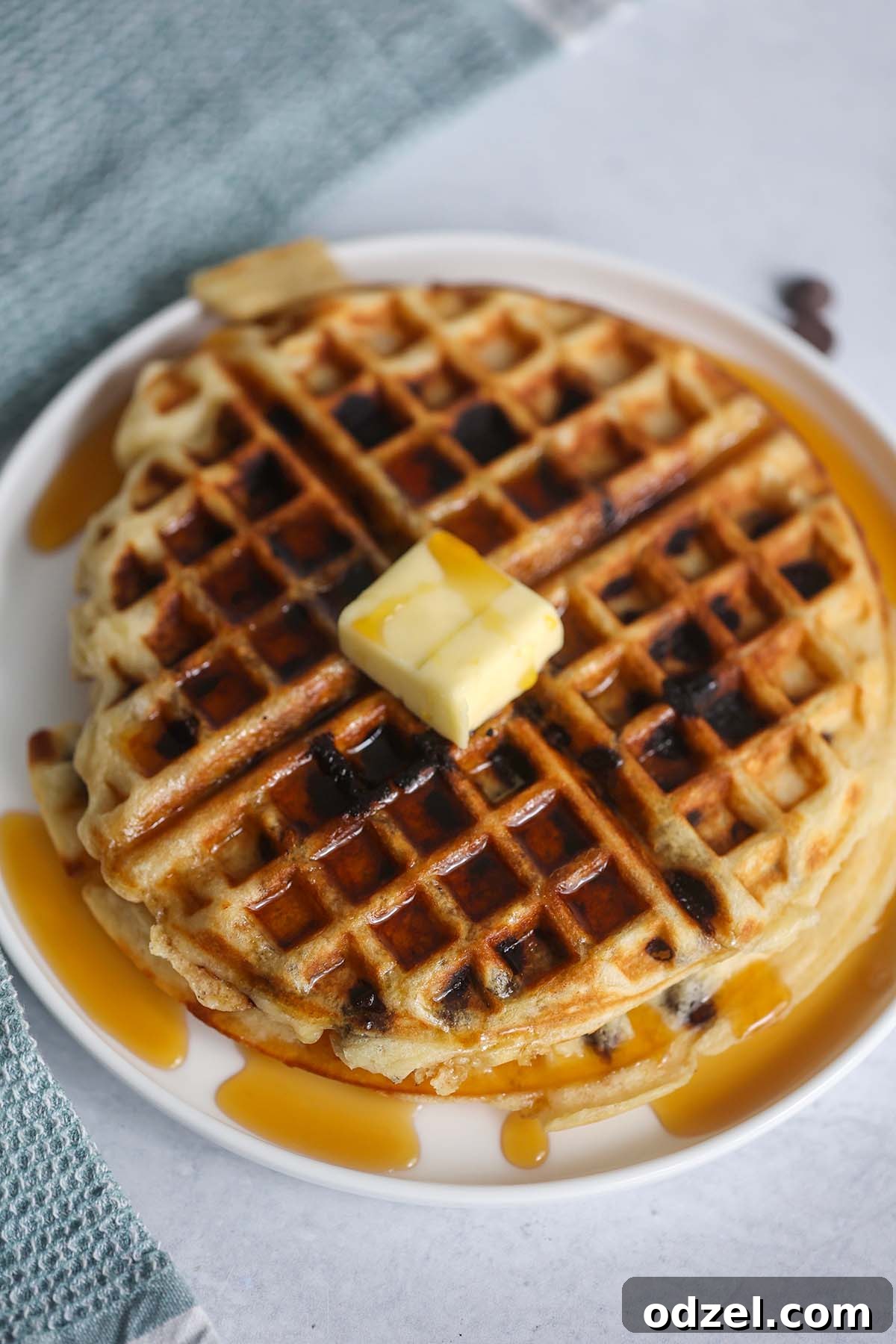 A single, perfectly cooked buttermilk chocolate chip waffle resting on a white plate, awaiting delicious toppings.