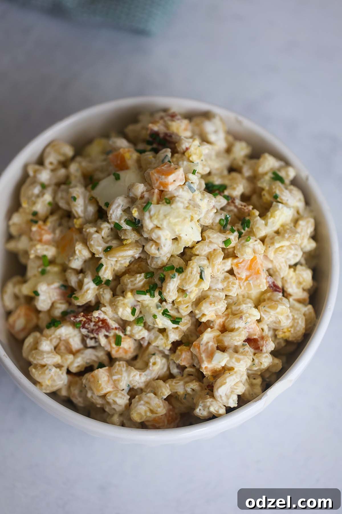 Decadent Bacon Ranch Pasta Salad 2 A large white bowl filled with creamy bacon ranch pasta salad, showcasing the golden pasta, crisp bacon pieces, and vibrant green chives, ready to be served.