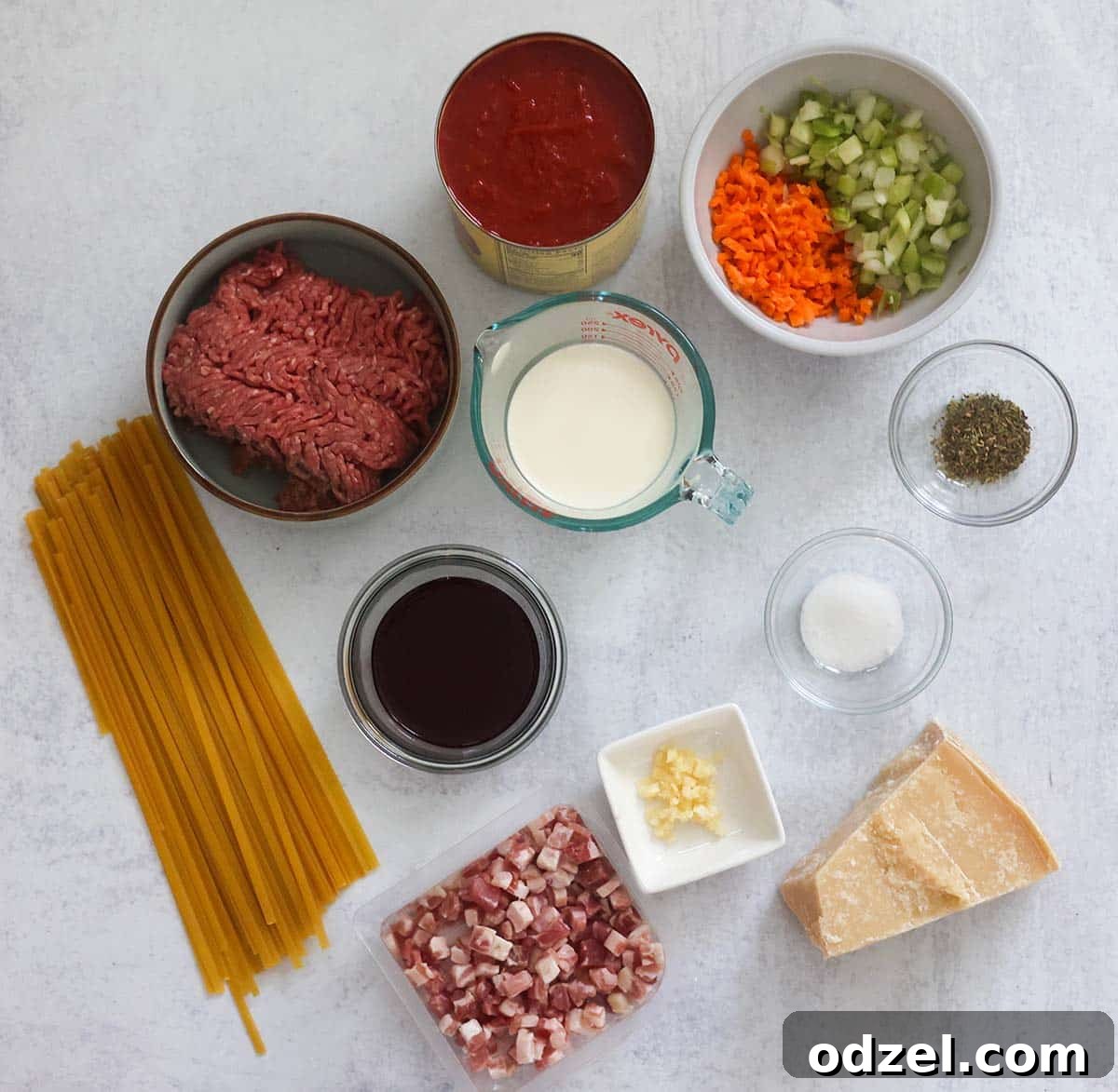 Slow-Simmered Bolognese with Fettuccine 3 A vibrant collection of fresh ingredients laid out on a wooden board, ready for making bolognese, including ground beef, pancetta, tomatoes, herbs, and vegetables.