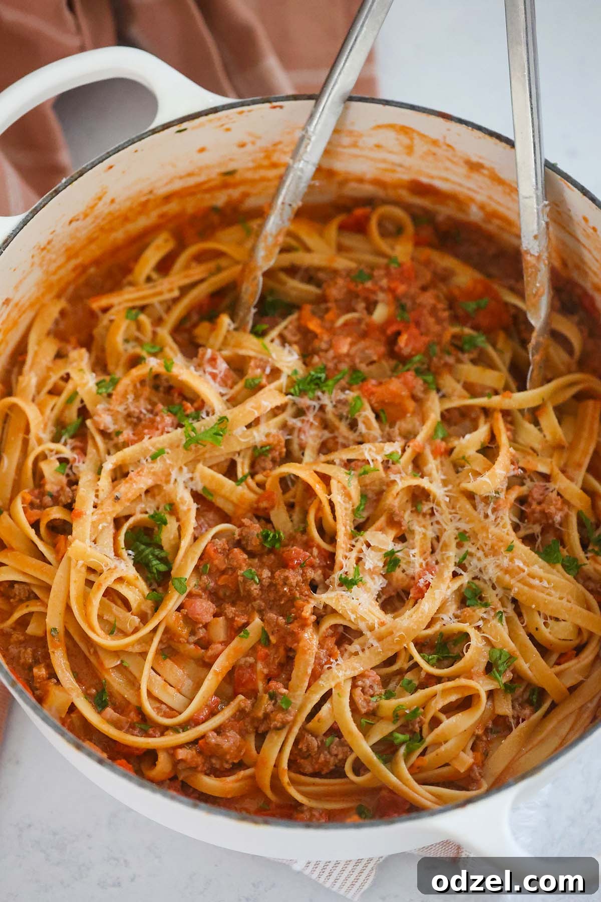 Slow-Simmered Bolognese with Fettuccine 6 A large pot filled with cooked fettuccine pasta being tossed with tongs, ready to be combined with the rich bolognese sauce.