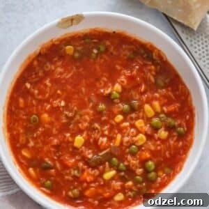 Alphabet soup in a white bowl with a block of parmesan cheese on the side.