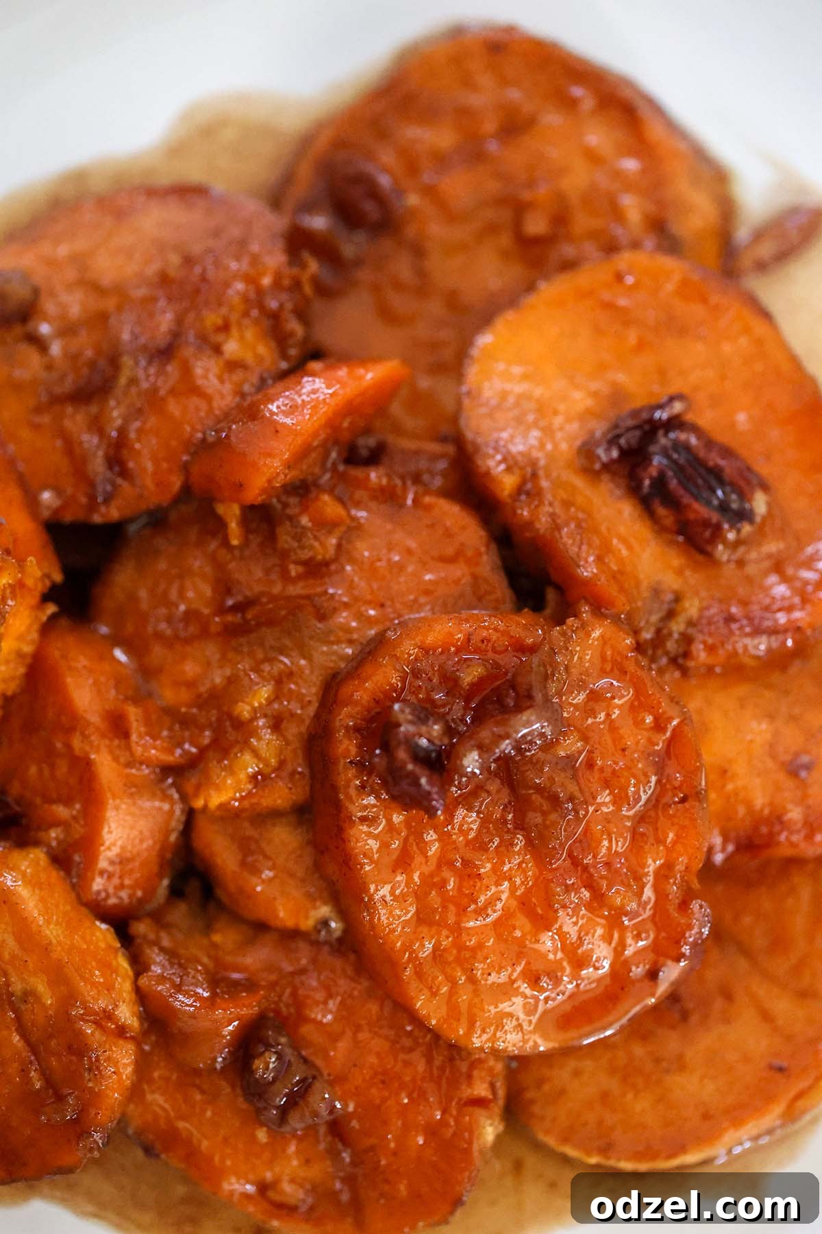 Caramelized Bourbon Yams 2 Rich, glistening bourbon candied yams with toasted pecans scattered on top, served in a festive white casserole dish.