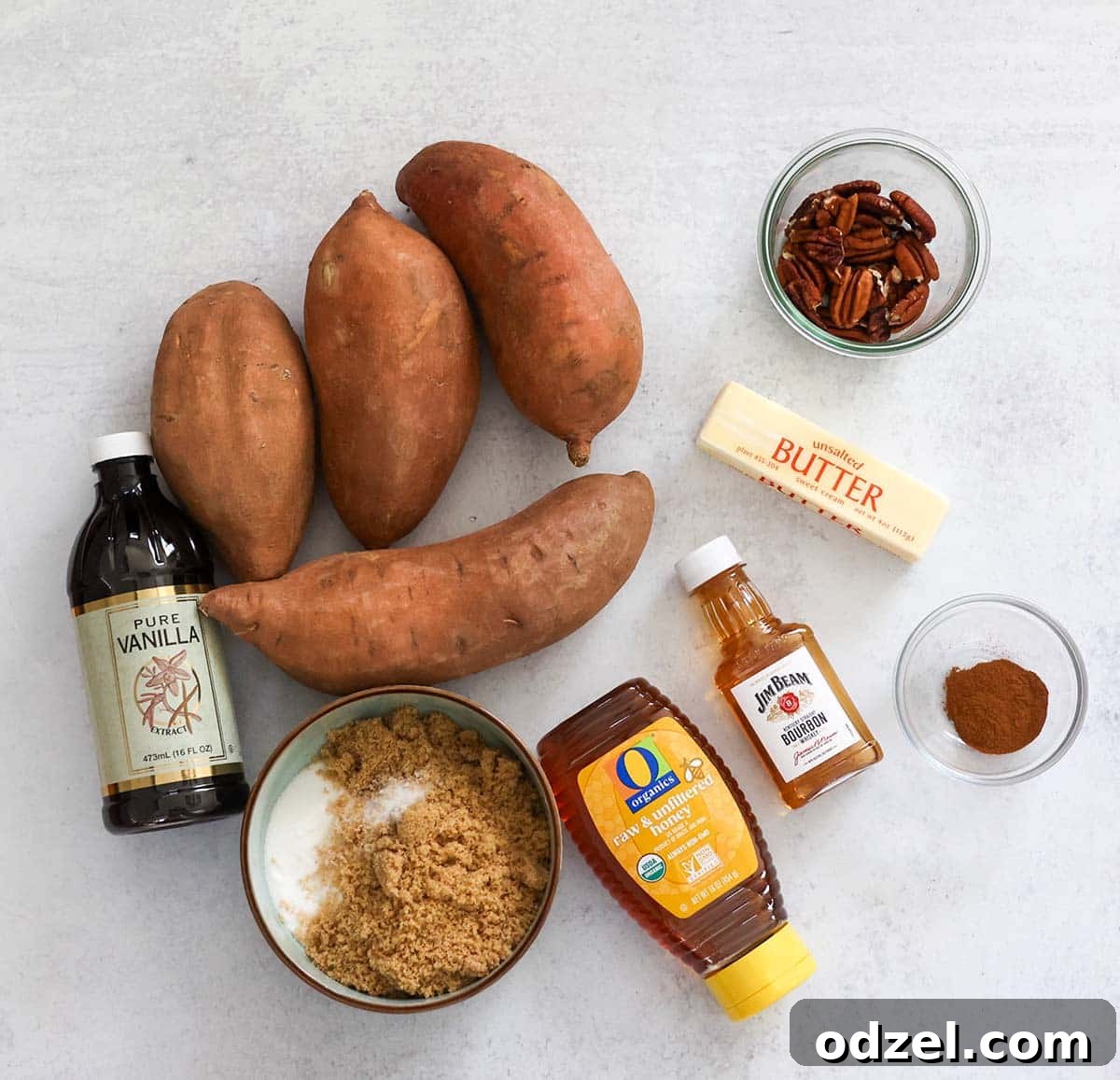Caramelized Bourbon Yams 3 A vibrant display of fresh ingredients neatly arranged for making bourbon candied yams, including bright orange yams, dark brown sugar, golden butter, crunchy pecans, and a bottle of fine bourbon.