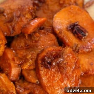 Closeup of bourbon candied yams with pecans, glistening with a rich glaze in a circular serving dish.