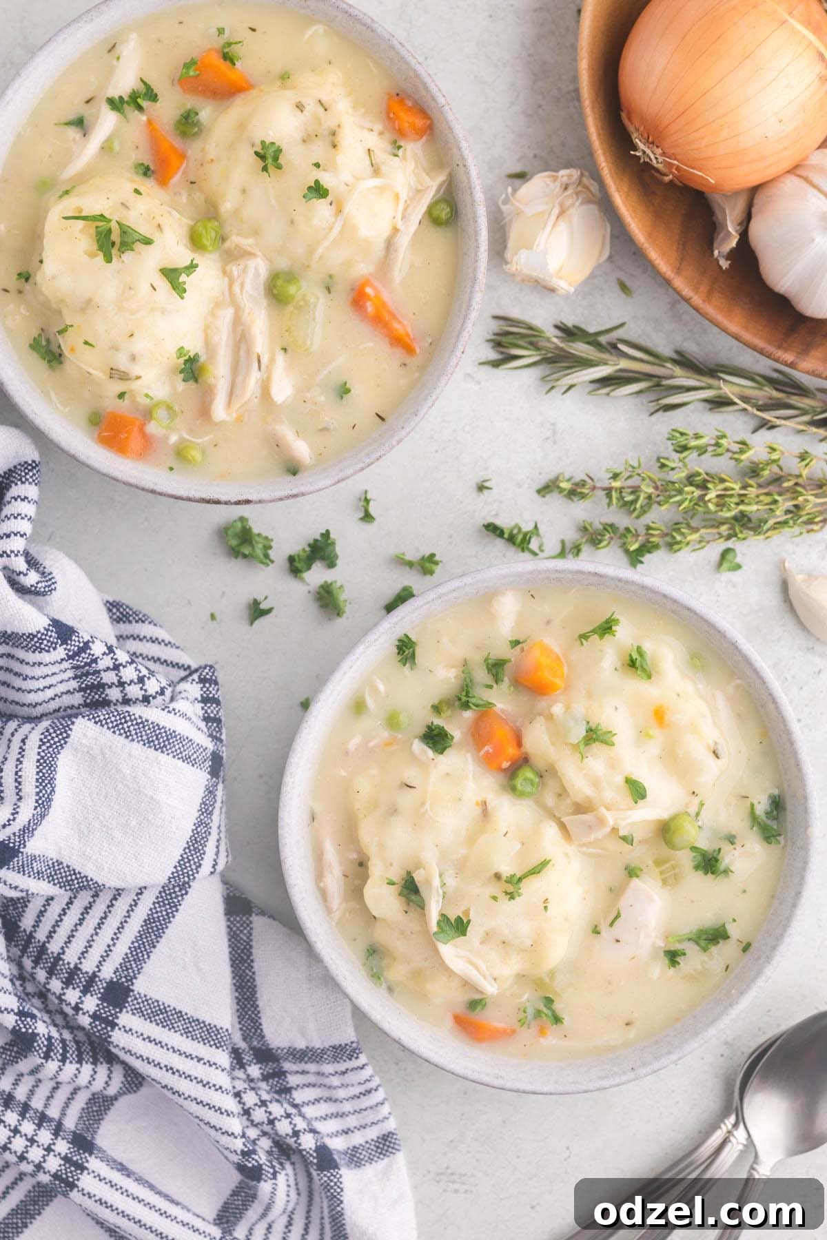 Two cozy bowls of homemade chicken and dumplings, garnished with fresh parsley, presented on a rustic wooden table, inviting viewers to enjoy this comforting meal.