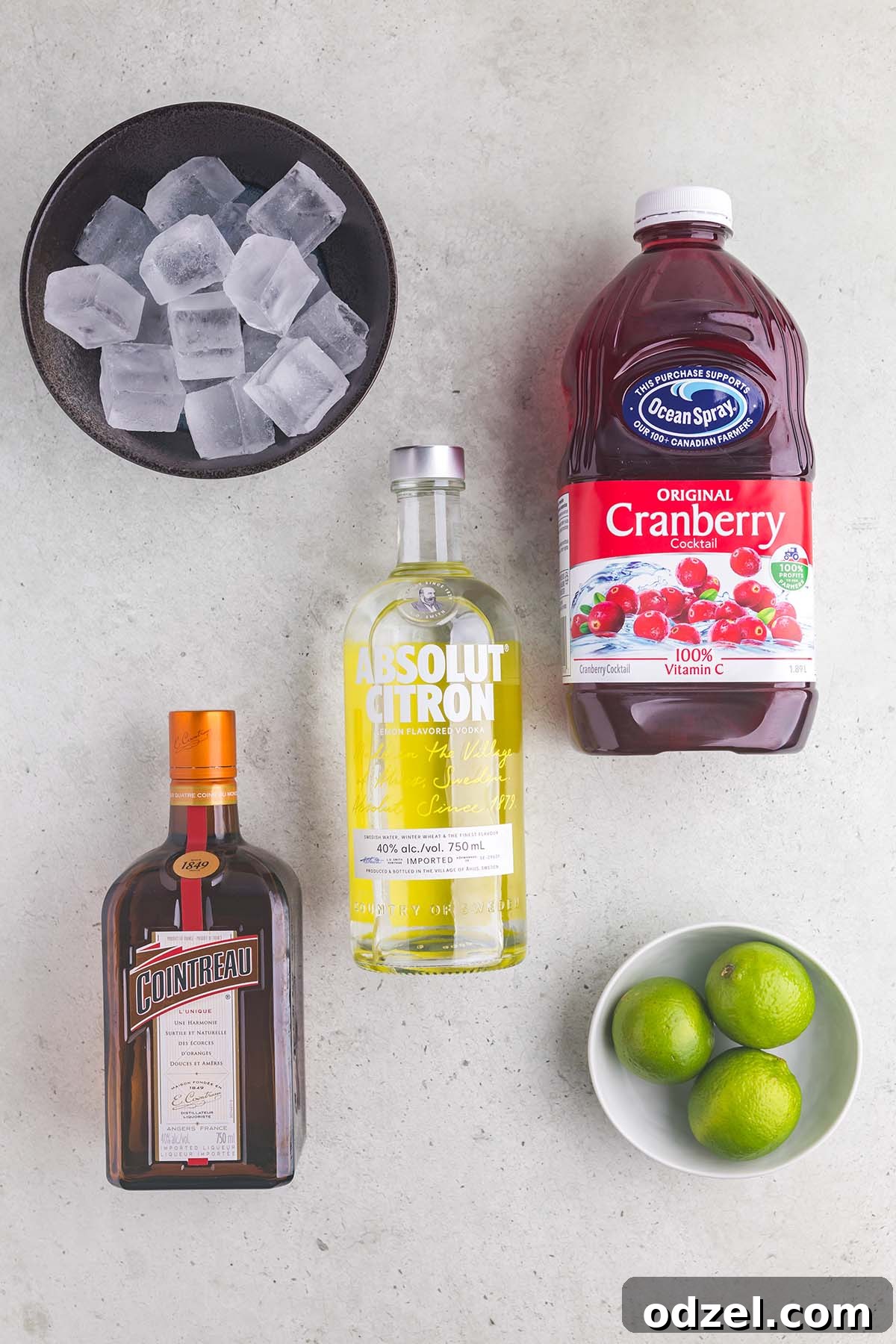 Carefully arranged ingredients for a Cosmopolitan cocktail, showcasing the fresh lime, cranberry juice, vodka, and Cointreau.
