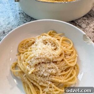 Buttered noodles in a bowl and a skillet in the background.