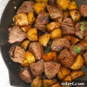 Steak bites and potato cubes in a skillet.
