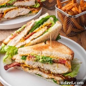 A chicken club sandwich with French fries on the side.