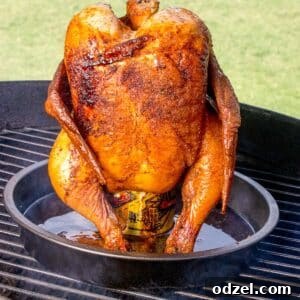 A whole chicken cooked upright on a beer can on the grill.