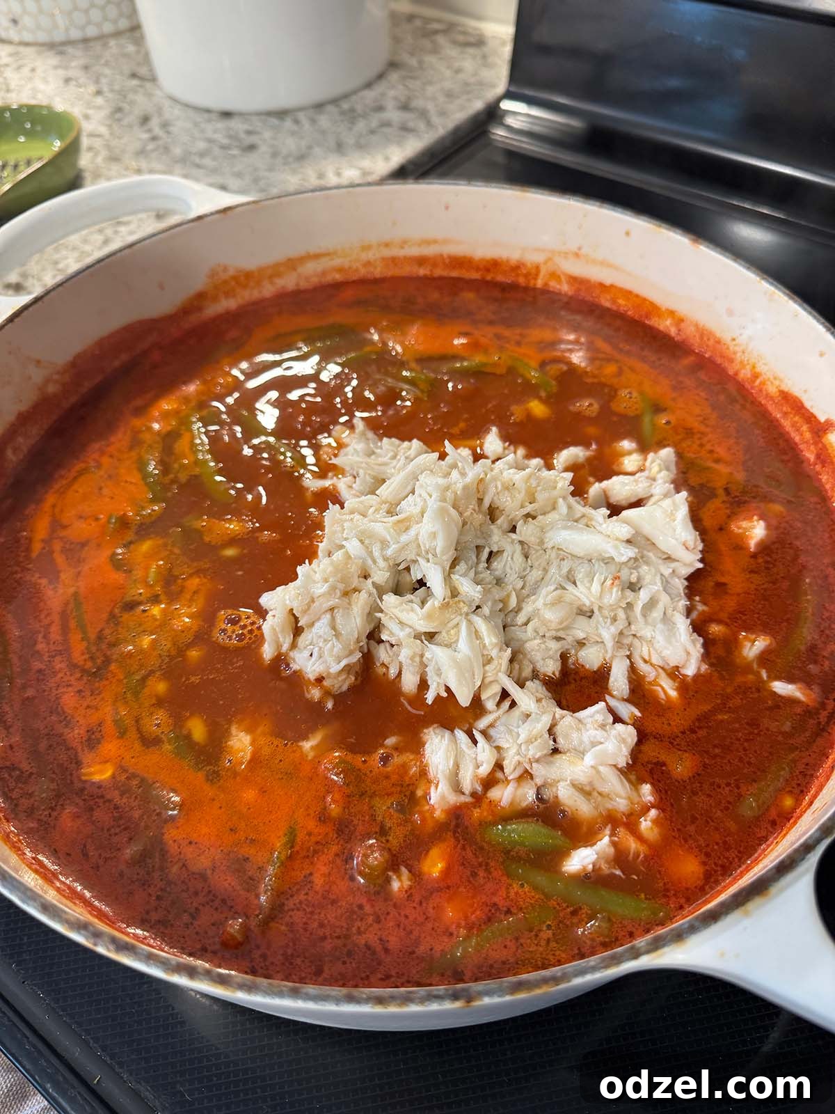 Maryland crab soup simmering gently on the stovetop, filled with vegetables and crab meat, releasing fragrant steam.