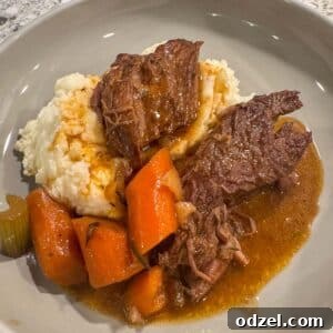 Slow cooker pot roast with mashed potatoes, rich gravy, and tender vegetables, presented as a comforting meal.