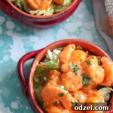 Close-up of golden-brown fried shrimp generously coated in a creamy mayo-based sauce, topped with fresh parsley.