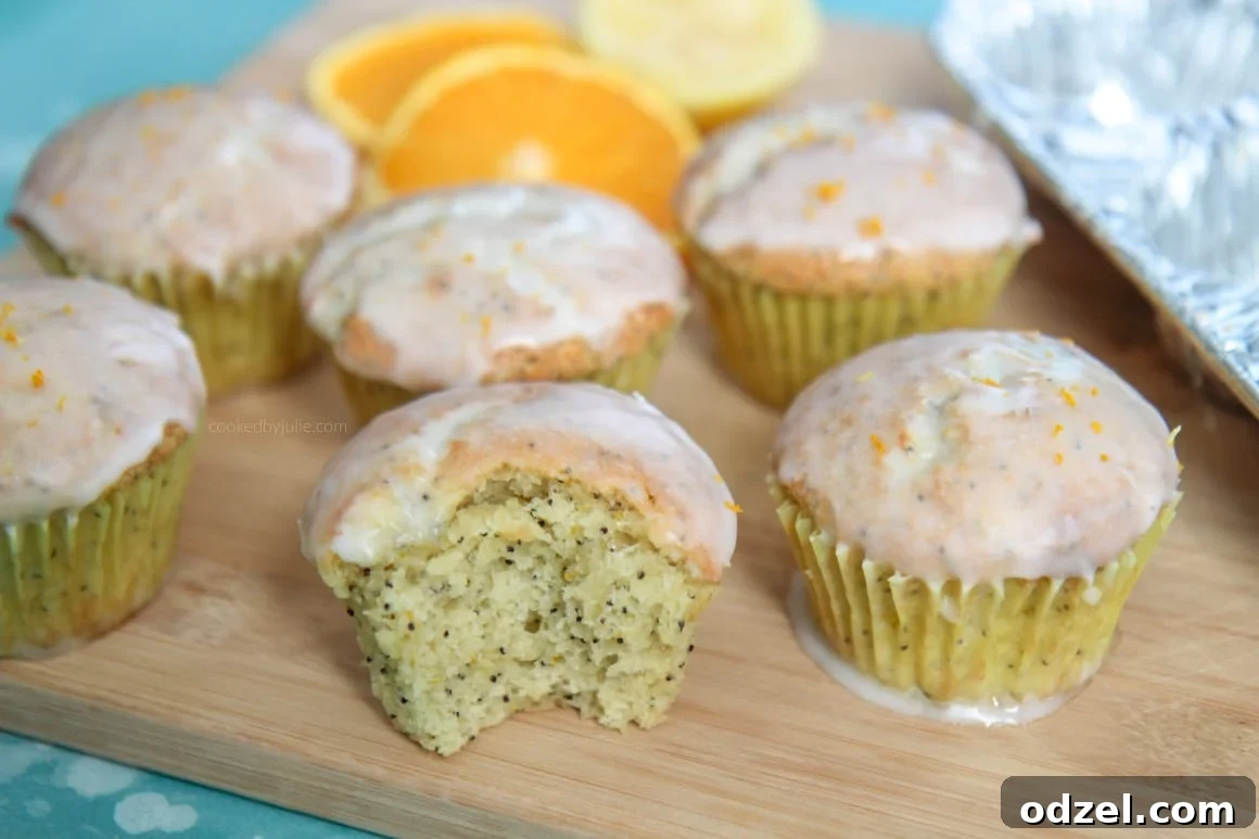A half-eaten orange lemon poppy seed muffin rests on a wooden board, showcasing its moist interior and the delicate poppy seeds within, promising a delicious bite.