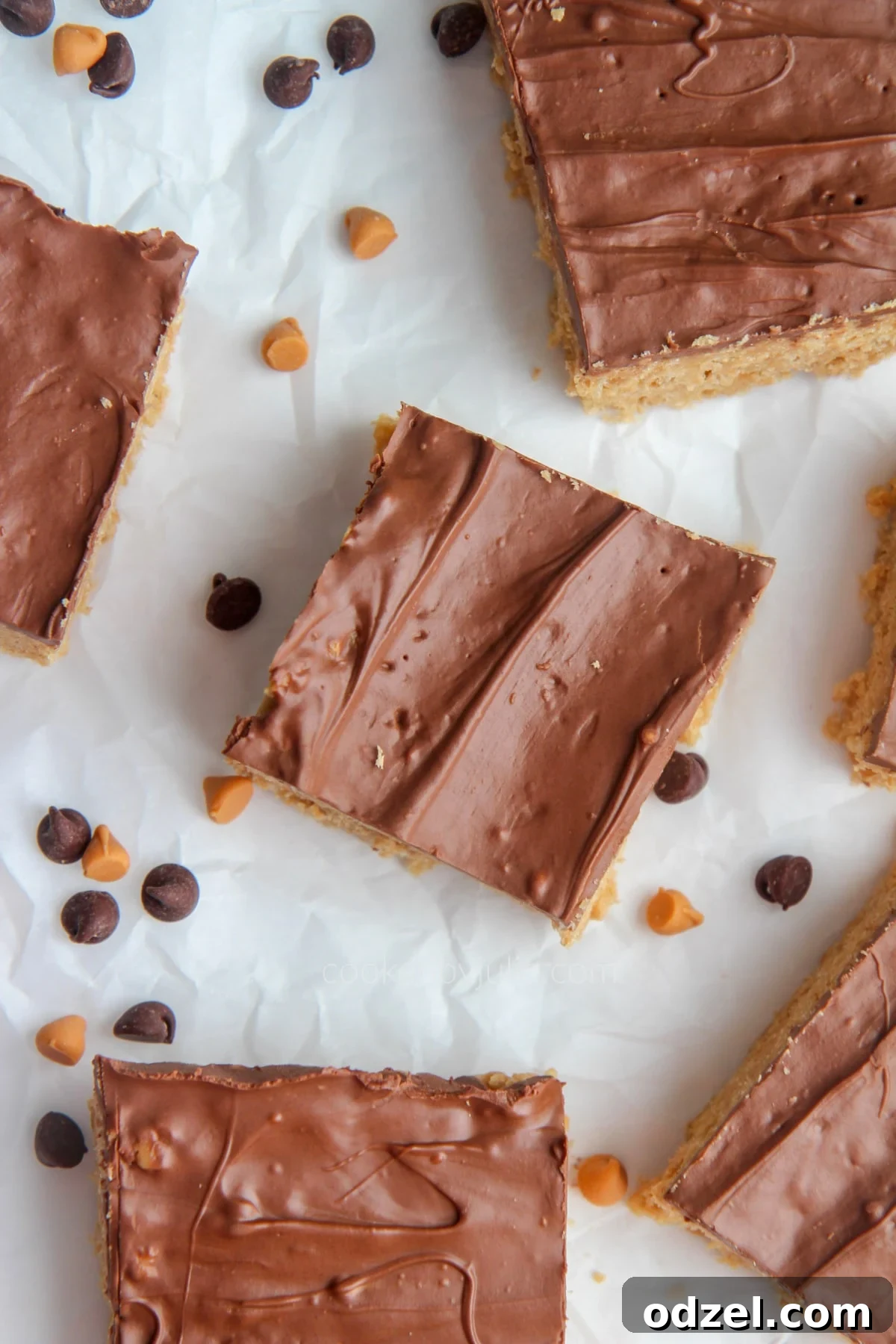 Scotcharoo slices beautifully arranged on parchment paper with a scattering of chocolate and butterscotch chips