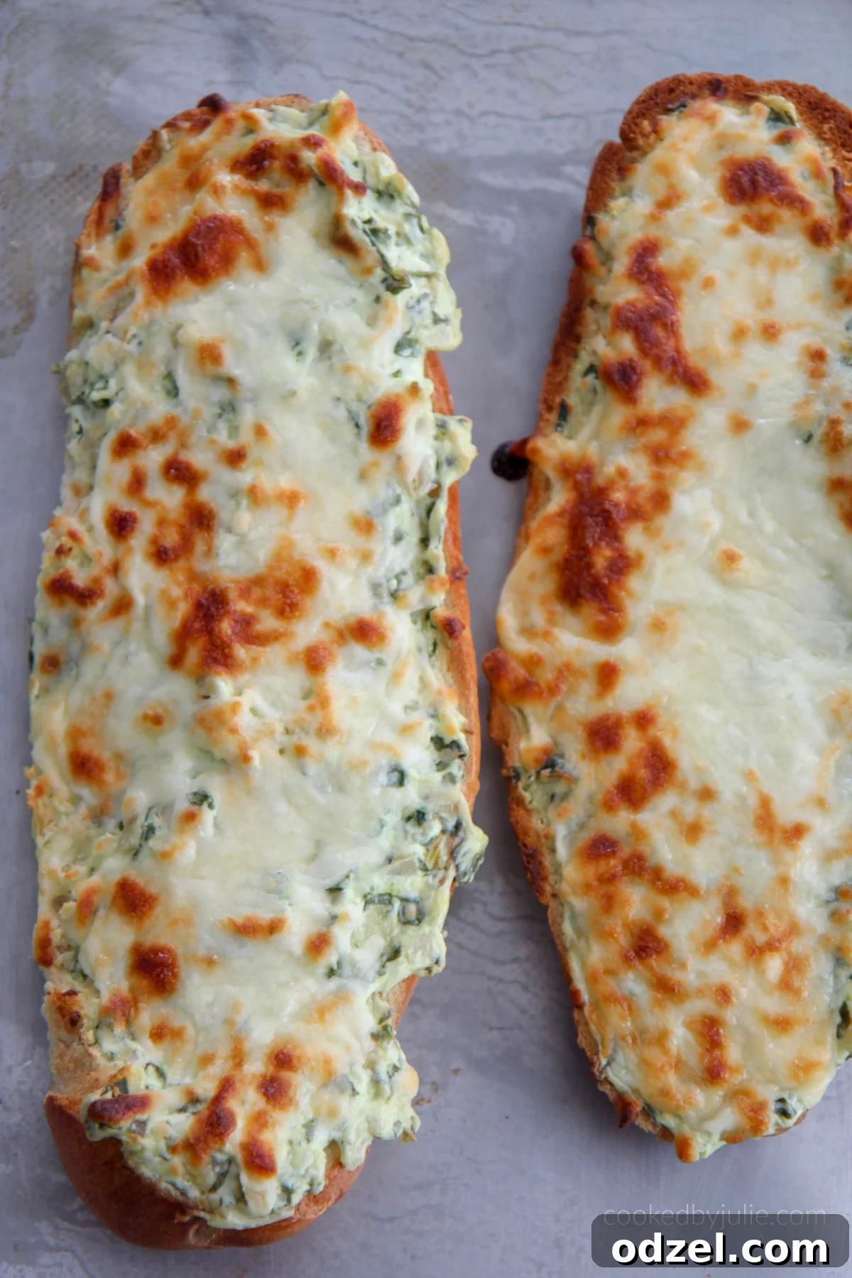 Spinach Artichoke Pull-Apart Loaf 2 Two golden-brown loaves of cheesy spinach artichoke bread on a baking sheet, ready to serve.