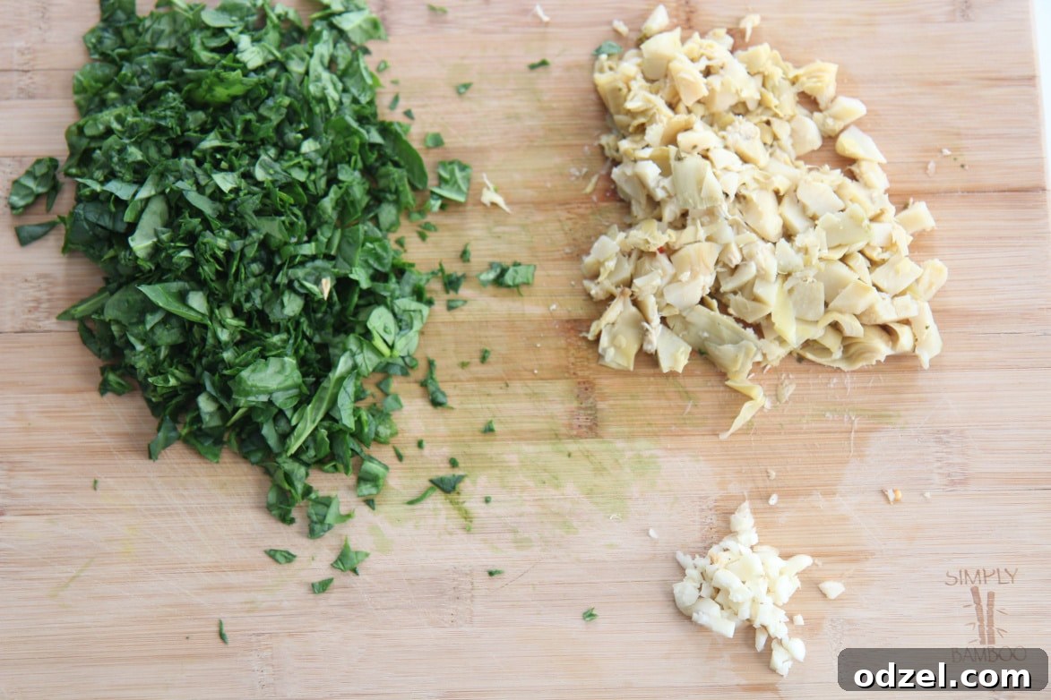 Spinach Artichoke Pull-Apart Loaf 3 A cutting board displaying fresh spinach, finely minced garlic cloves, and roughly chopped canned artichoke hearts, ready for the dip.