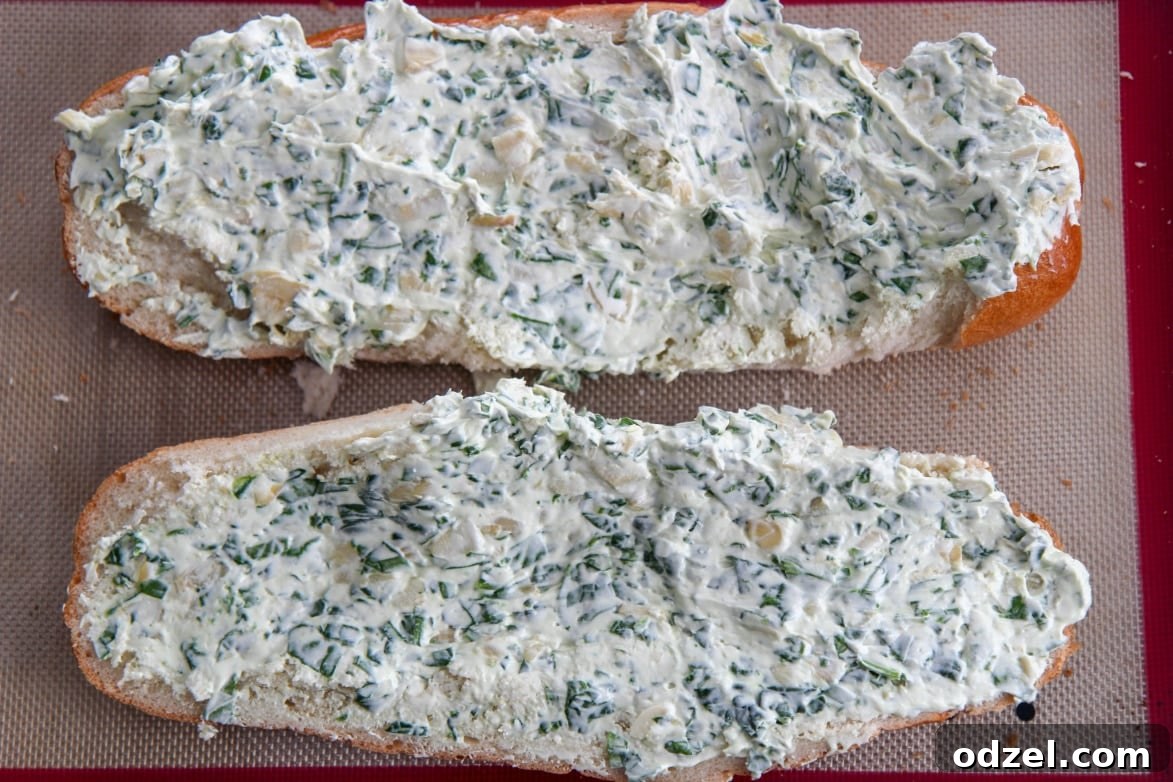 Spinach Artichoke Pull-Apart Loaf 5 French bread slices generously smeared with creamy spinach artichoke mixture, ready for cheese and baking.
