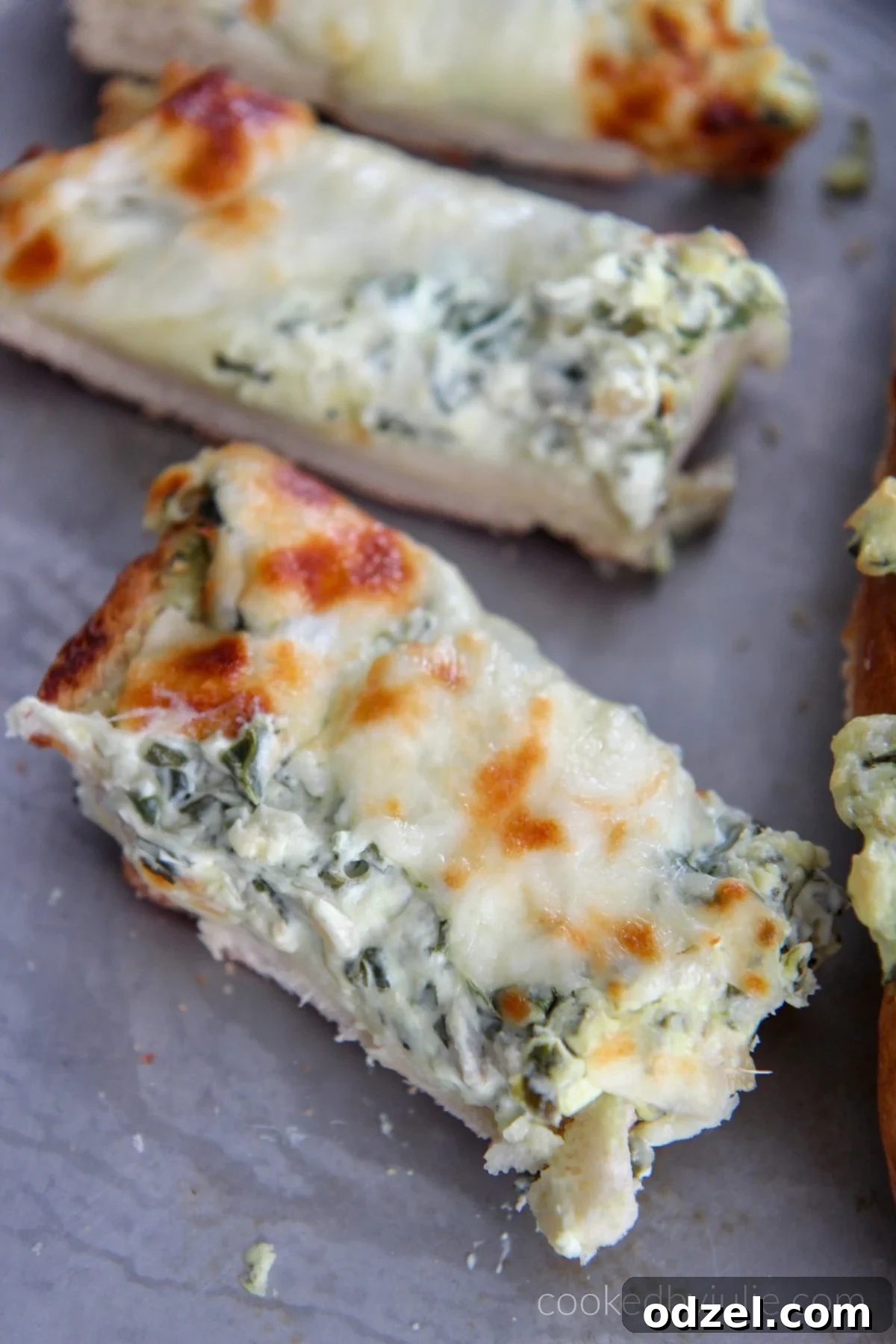 Spinach Artichoke Pull-Apart Loaf 6 Several slices of freshly baked spinach artichoke cheese bread on a baking sheet, showcasing melted cheese and golden crust.
