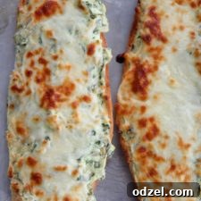 Two loaves of cheesy spinach artichoke bread on a baking sheet