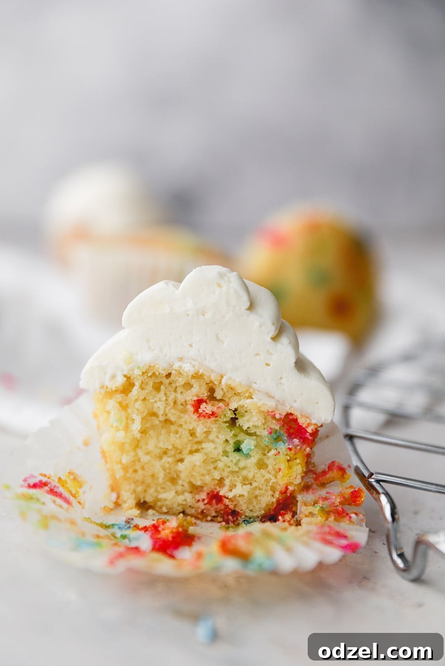 Celebration Funfetti Cupcakes 3 A funfetti cupcake sliced in half, showing the vibrant sprinkles embedded within the cake.