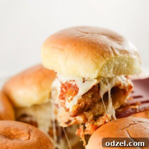 A spatula lifting a chicken parm slider from a the baking pan.