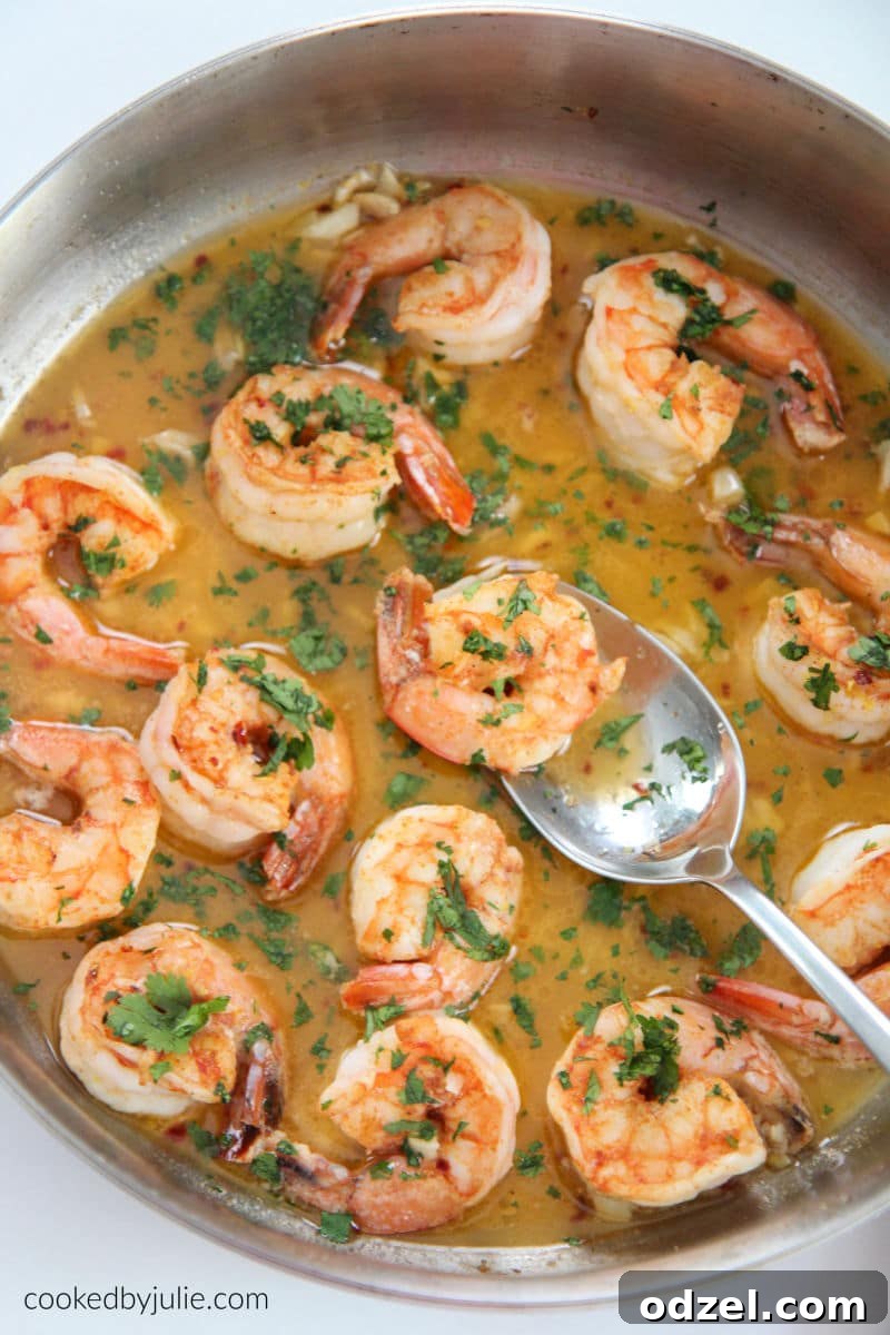 Shrimp Scampi in a skillet garnished with fresh parsley and a spoon, ready to serve.