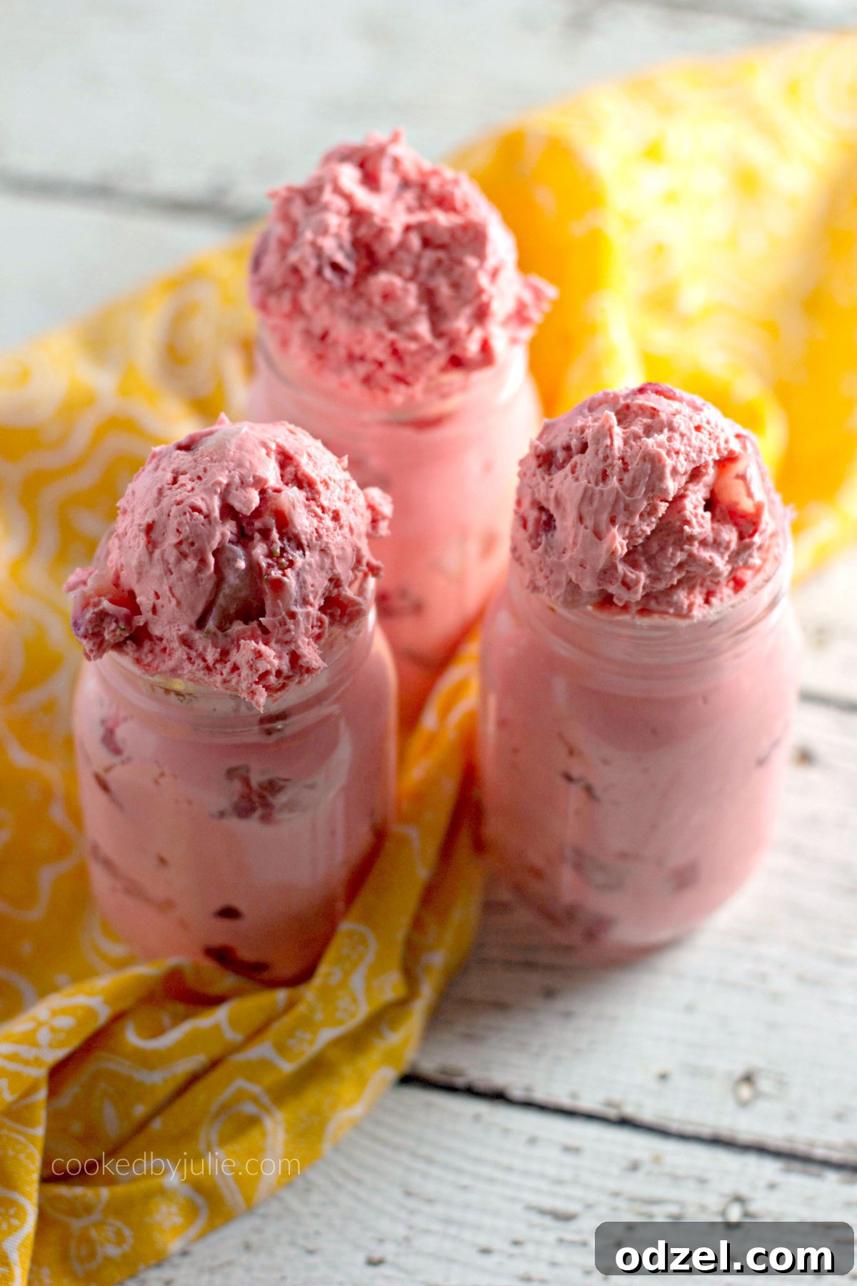 Delicious strawberry fat bombs served in elegant mason jars, adorned with a cozy yellow towel on the side, highlighting their creamy texture and fresh strawberry pieces.