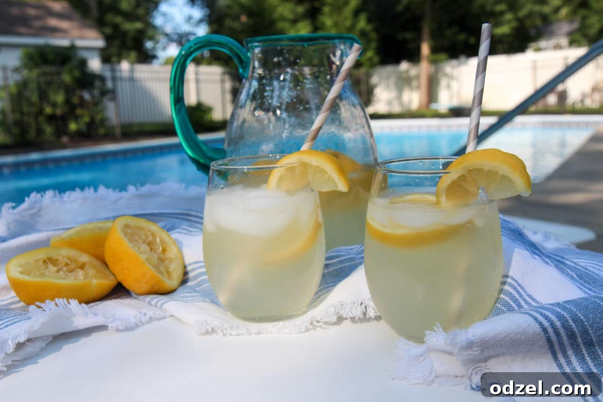 a pitcher and 2 glasses with fresh lemonade outside by the pool.