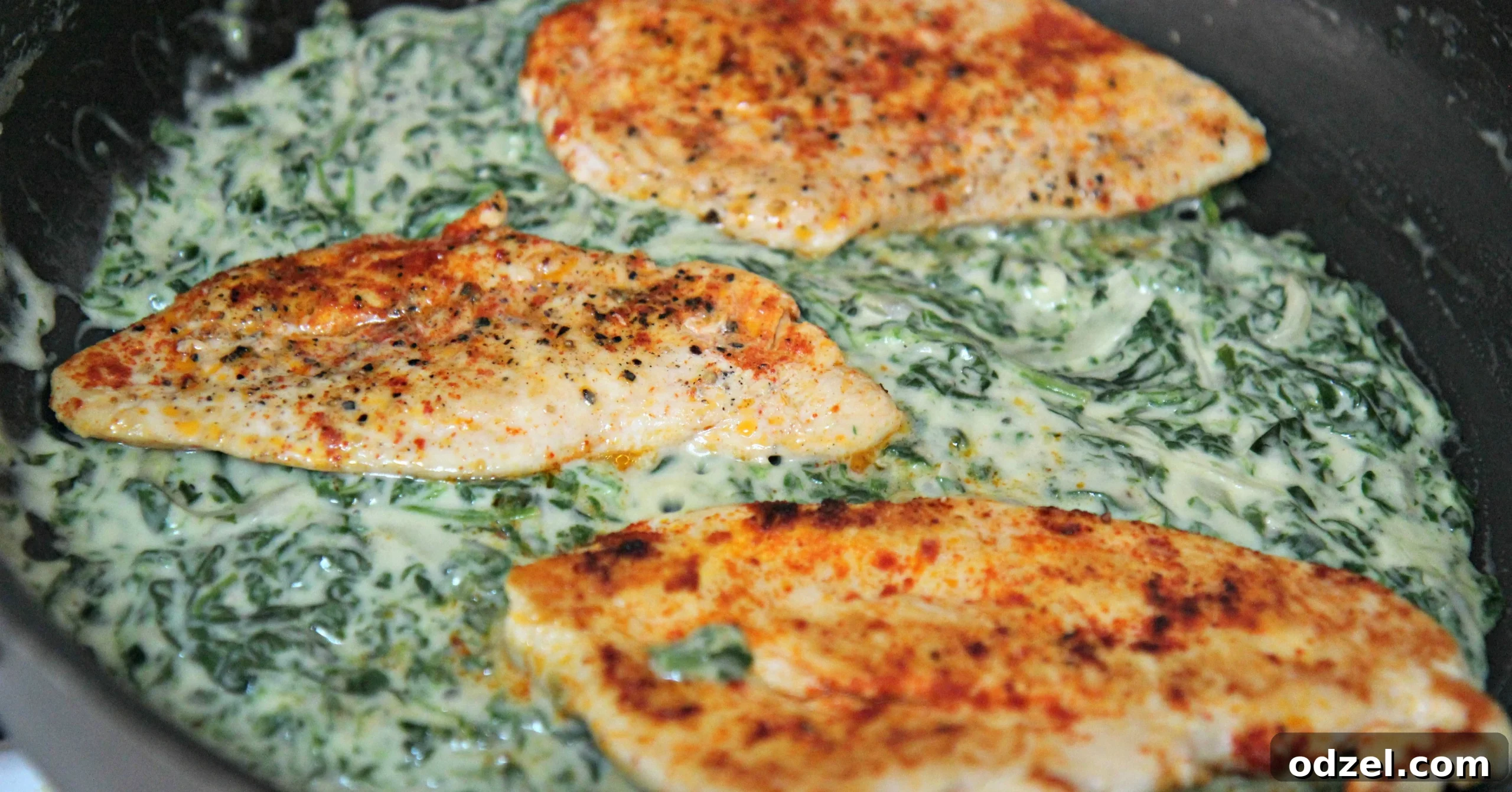 Close-up of perfectly seasoned chicken breast nestled in a vibrant green creamy spinach sauce