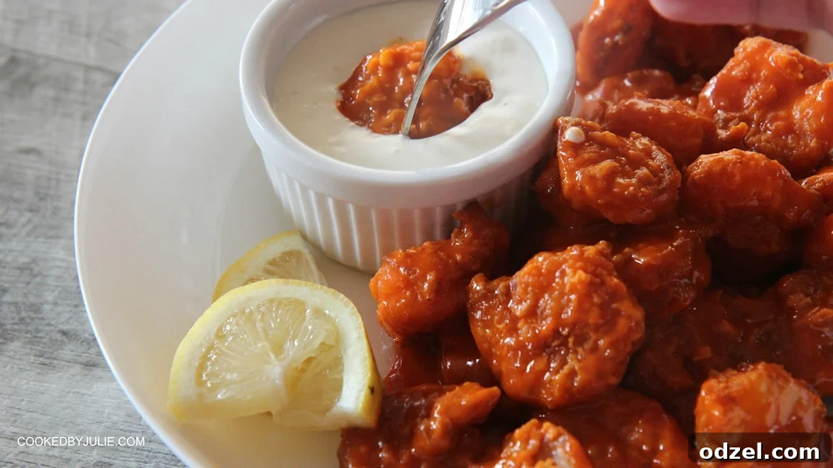A bowl of buffalo shrimp is prominently featured, with one shrimp captured mid-dip into a side of creamy blue cheese dressing, held by a fork.