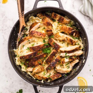 Cajun chicken, farfalle pasta, parsley, and a wooden spoon in a black skillet.