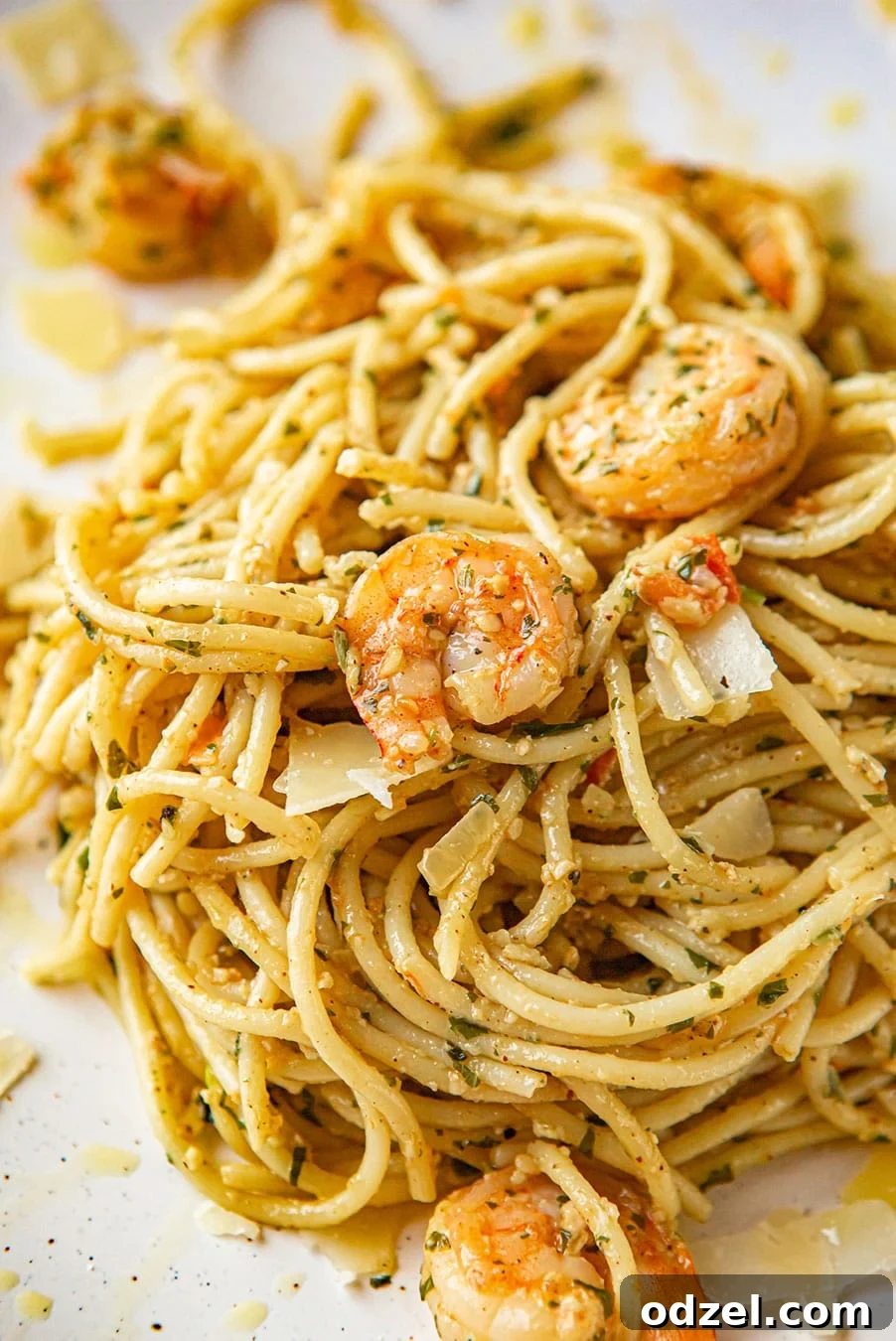shrimp pesto spaghetti on a white plate up close.