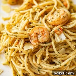 shrimp pesto spaghetti on a white plate up close.